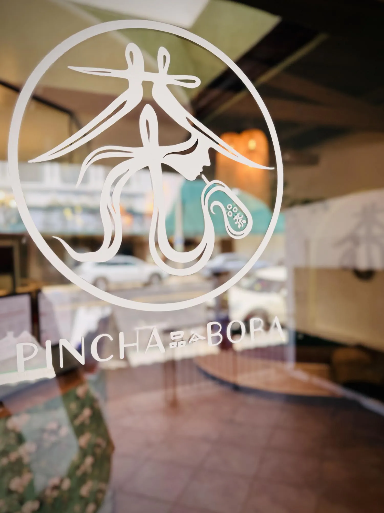 Pincha Boba Logo Displayed on Glass Window Inside a Contemporary Tea Shop